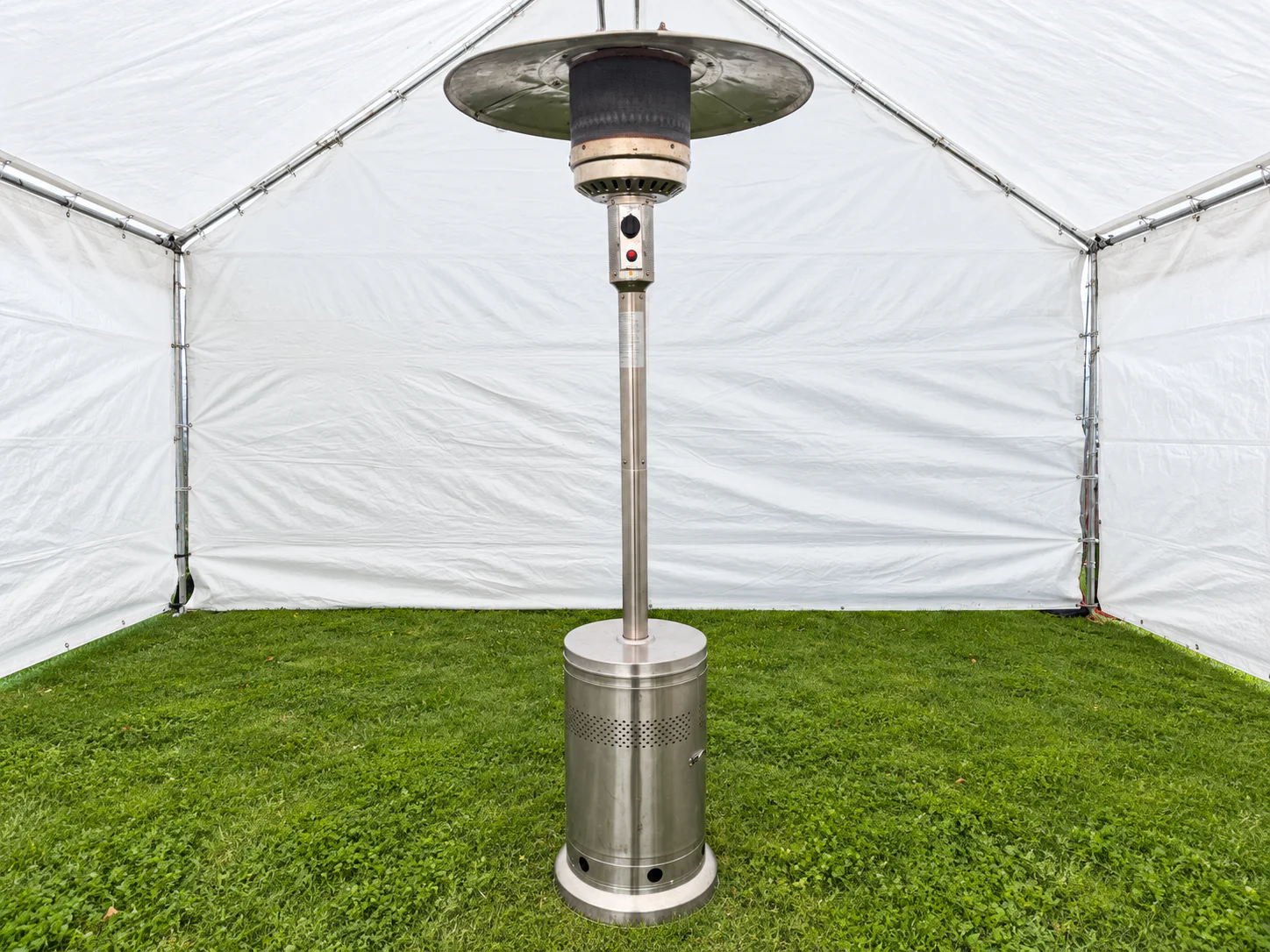 Stainless-steel outdoor patio heater standing inside a white canopy